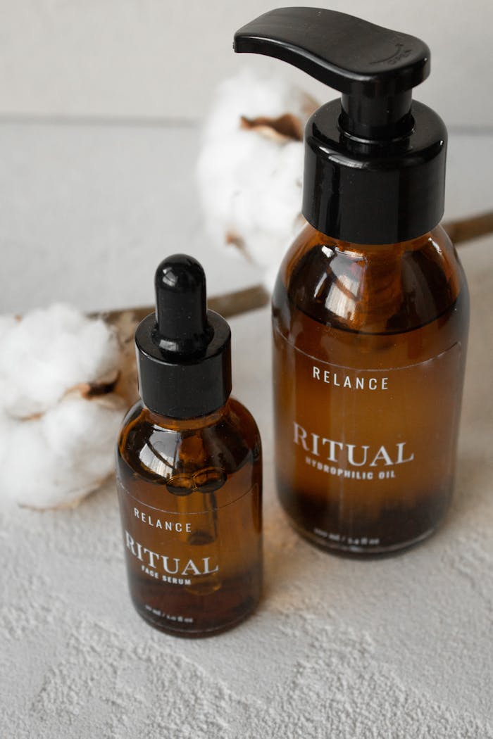 High-angle shot of cosmetic serum and oil bottles with cotton for skincare.